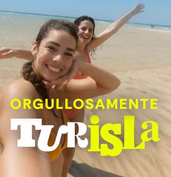 Dos personas disfrutando en la orilla de una playa de arena clara junto al mar.