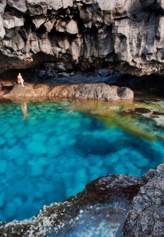 Charco Azul de El Hierro, una poza natural de aguas turquesas rodeada de roca volcánica oscura bajo un acantilado.