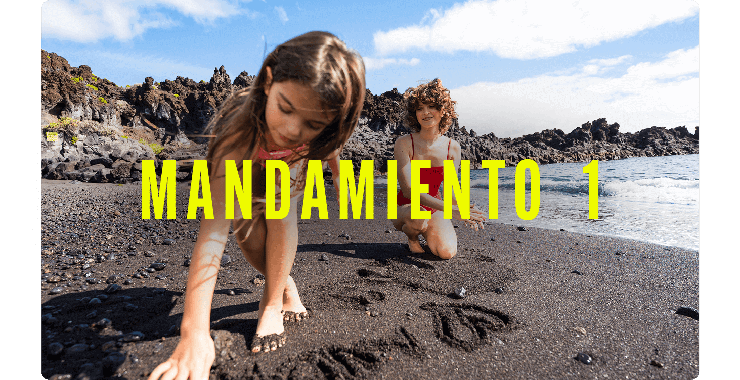 Criaturas en una playa de arena negra junto a formaciones volcánicas, dibujando en la arena cerca del agua.