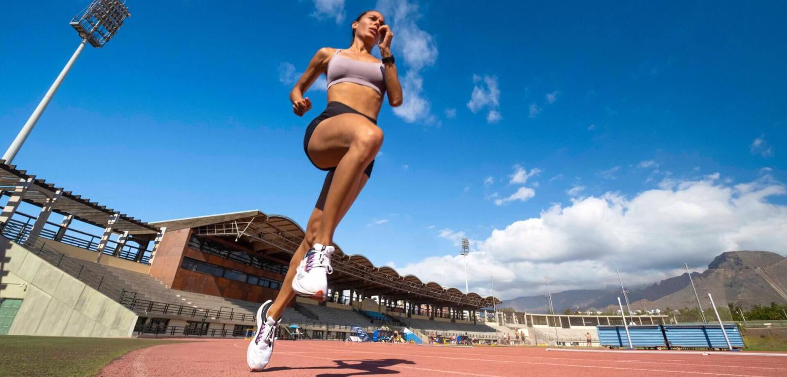 Atleta entrenando en una pista de atletismo al aire libre.
