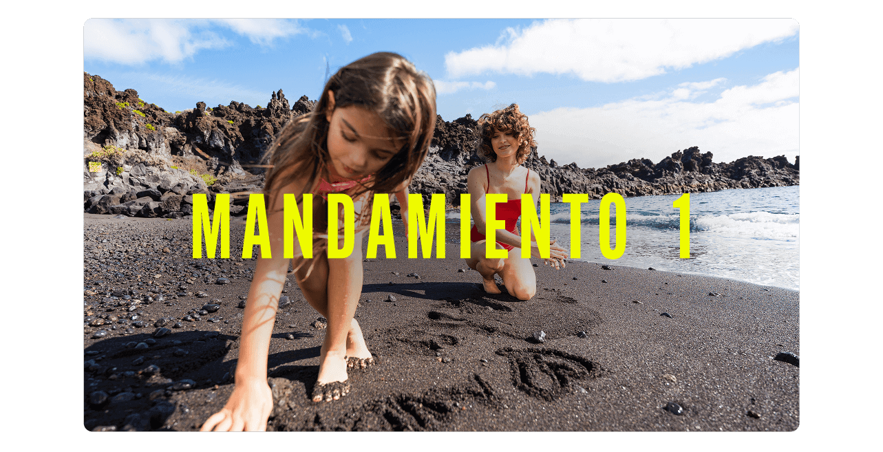 Criaturas en una playa de arena negra junto a formaciones volcánicas, dibujando en la arena cerca del agua.