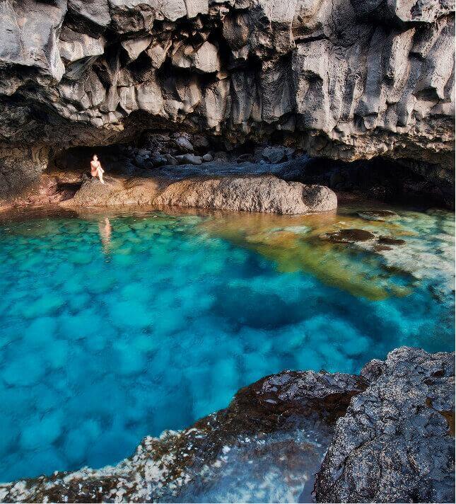 Charco Azul de El Hierro, una poza natural de aguas turquesas rodeada de roca volcánica oscura bajo un acantilado.